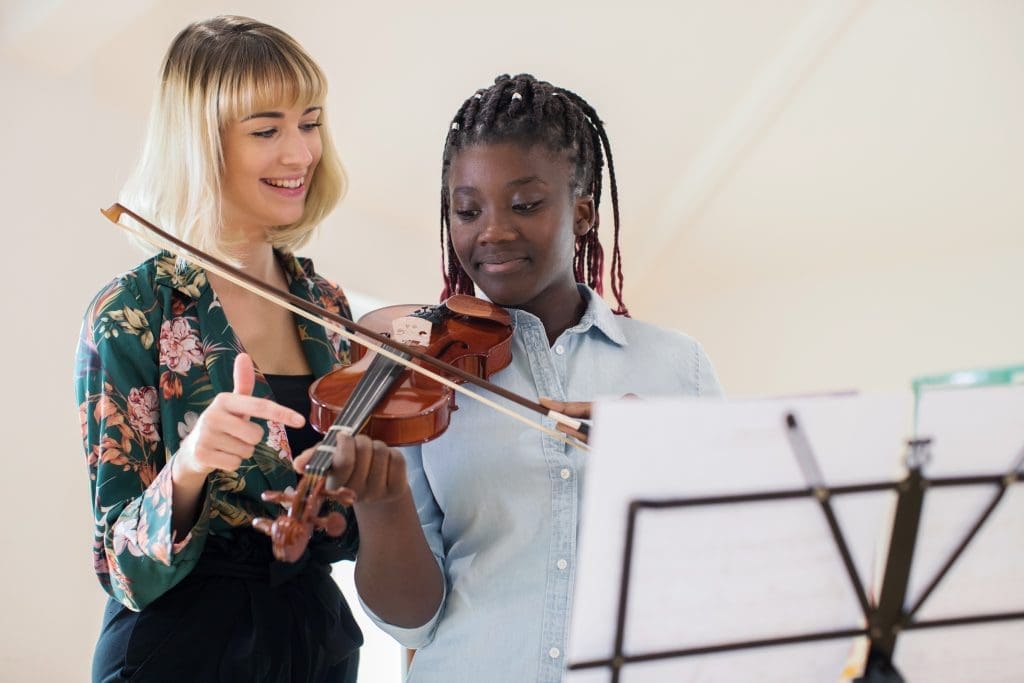 Tutor Teaching High School Student To Play Violin In Music Lesso