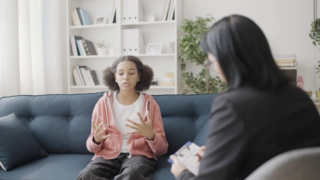 Teen talks to therapist about trauma from school shooting.