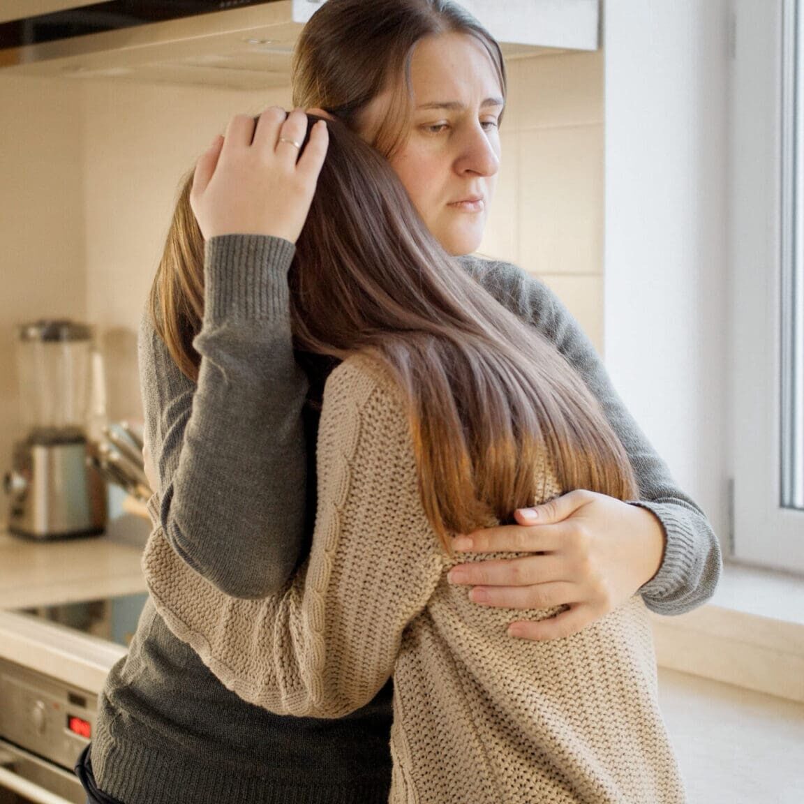 Young mother hugging and consoling her daughter talking about problems and depression. Parent supporting and comforting child Young mother hugging and consoling her daughter talking about problems and depression. Parent supporting and comforting child.